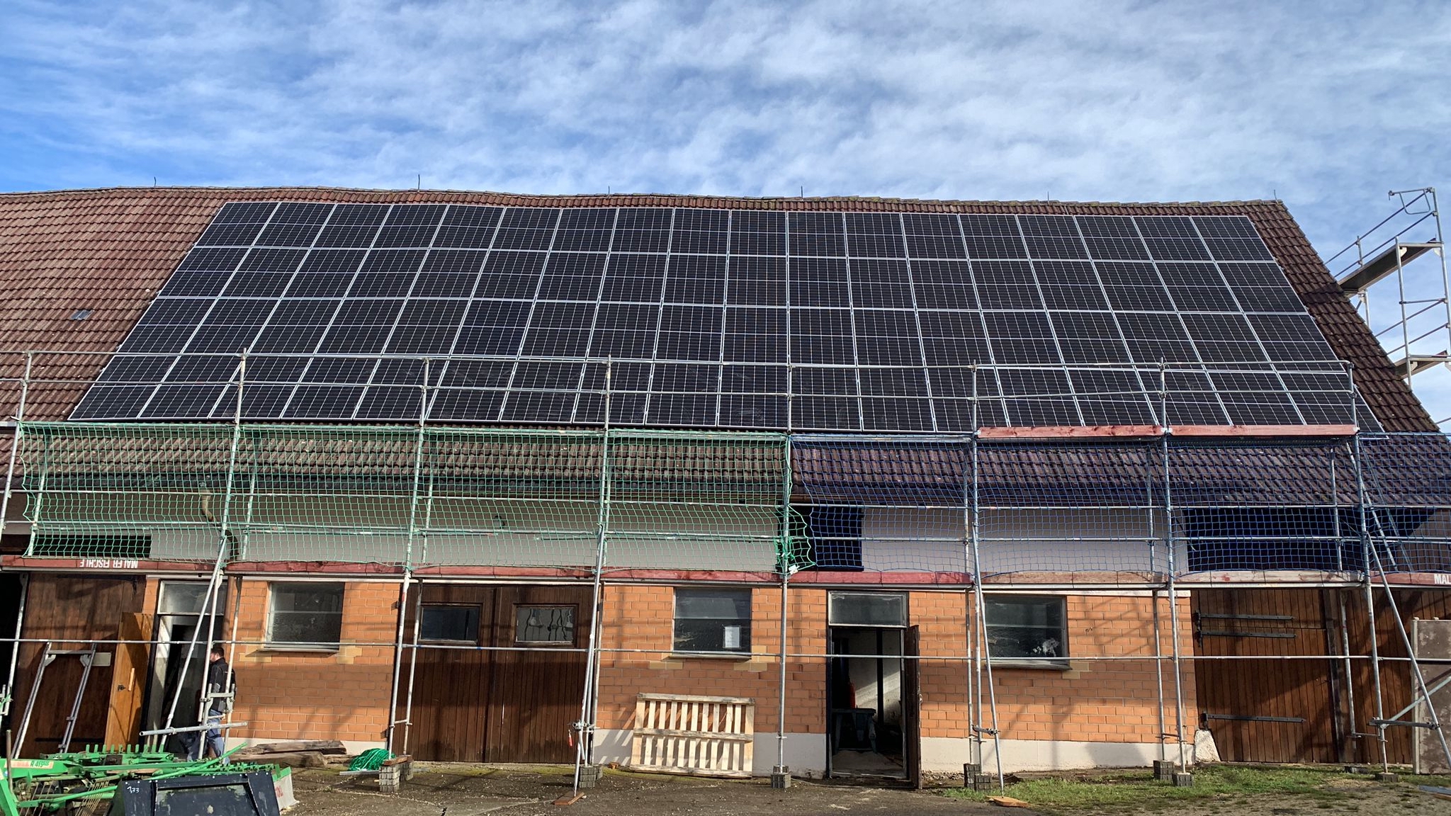 72 PV Paneele auf einer Scheune montiert. Um die Scheune steht noch das Gerüst. Die Anlage liefert grob 32 kWP Leistung.